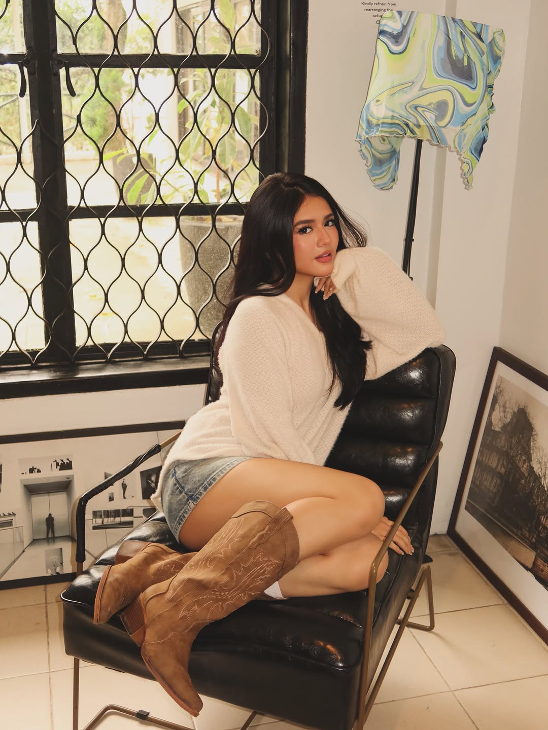 Sabrina Cuervo in a yellow dress and cowboy boots, holding a matcha at a cafe