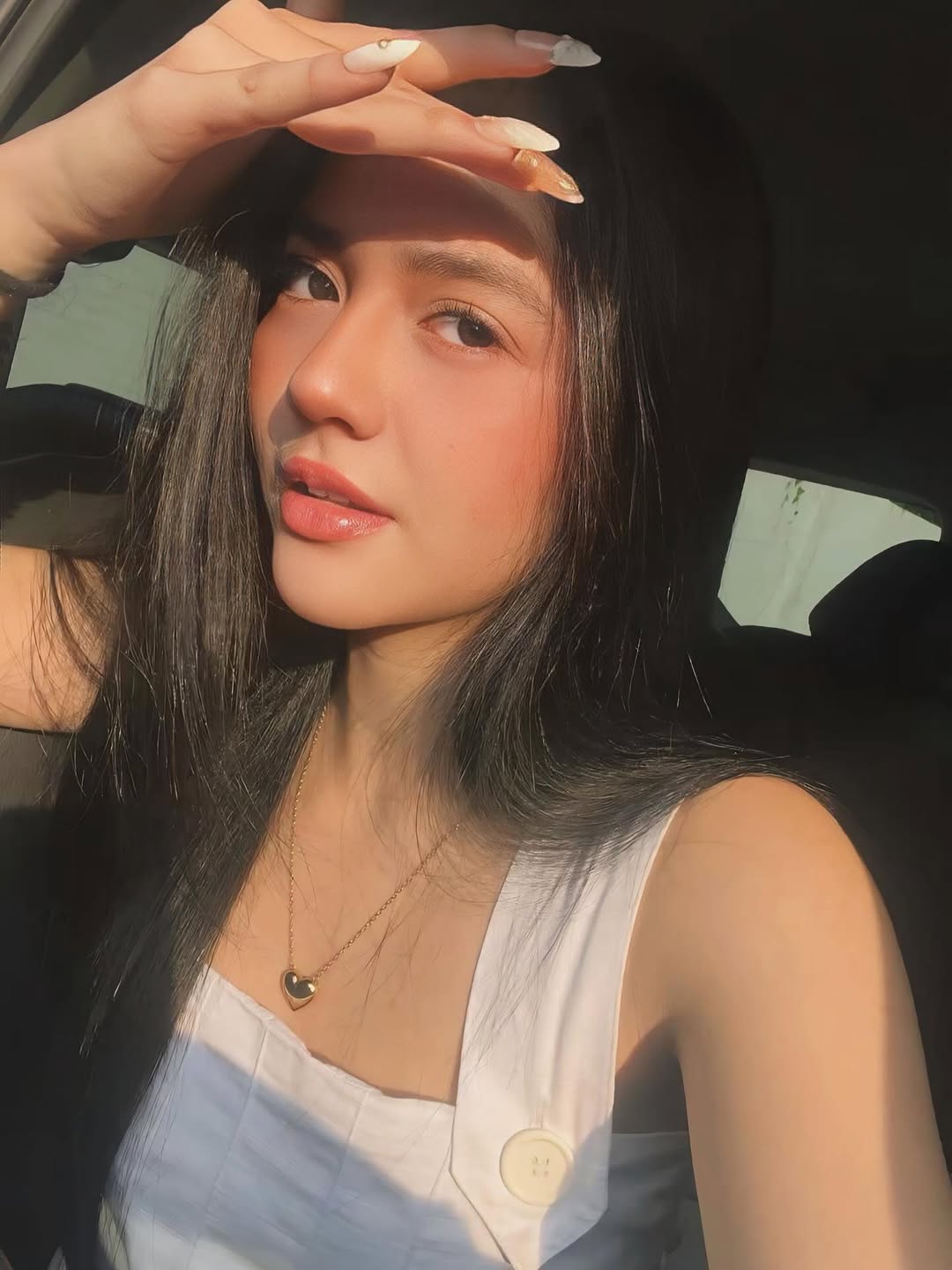 Sabrina Cuervo in a white shirt at golden hour, holding her phone up to the light