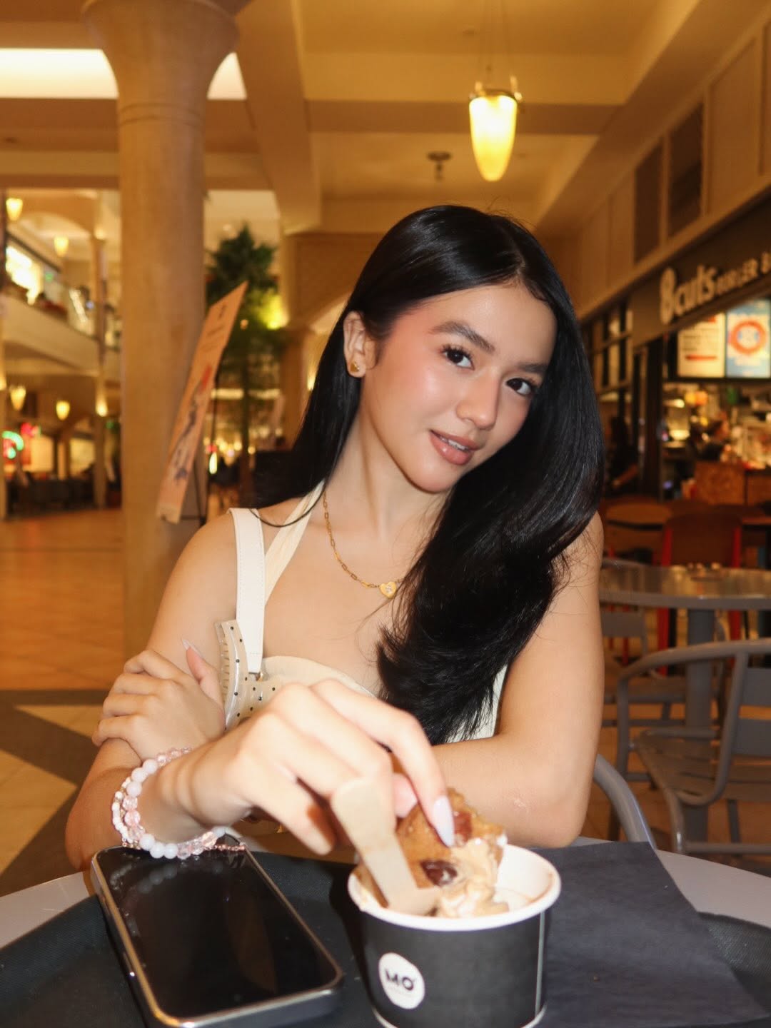 Sabrina Cuervo holding an ice cream cone beside Kayla Davies at a cafe table